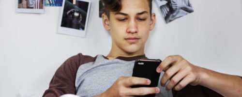Foto tienerjongen zit op mobiele telefoon